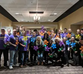 America’s Retirement Headquarters team and clients at community awareness event holding colorful flower props